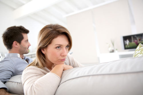 a couple sitting on a couch with the woman turned away from the man