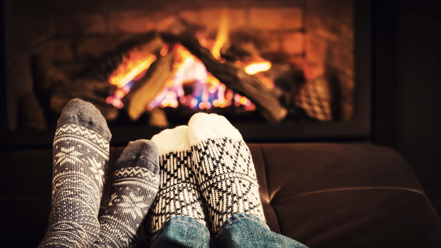 two pairs of feet in front of a fireplace