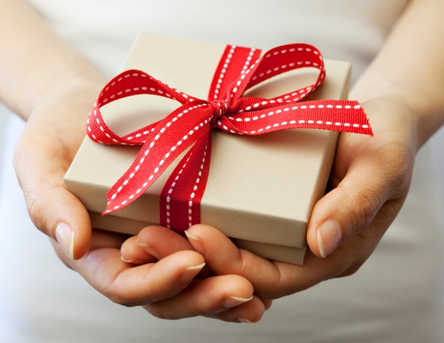 a woman holding out a gift with a bow in it