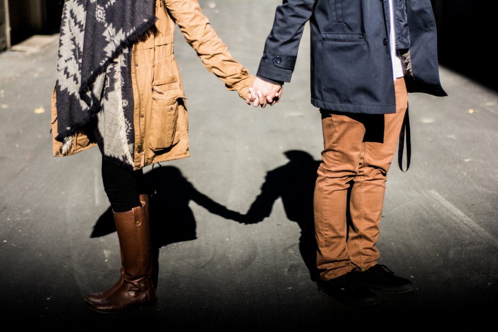 a couple holding hands but standing far apart and facing away from each other