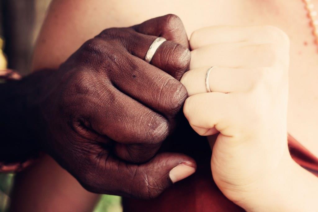 A man and wife holding hands with their wedding rings on.