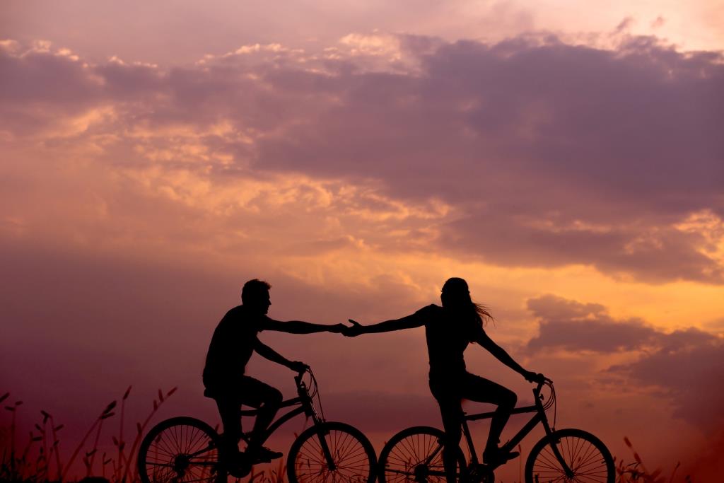 A couple biking together at sunset.