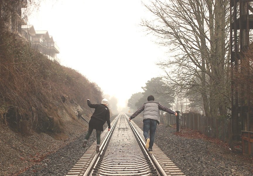 A couple walking on the traintracks.