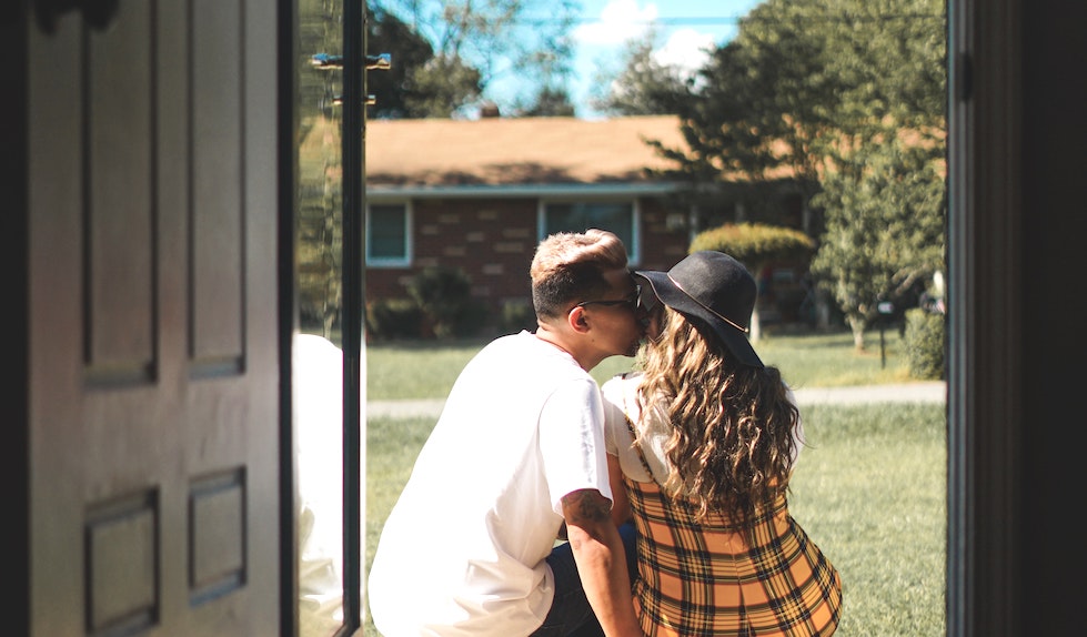 A couple kissing on a doorstep.