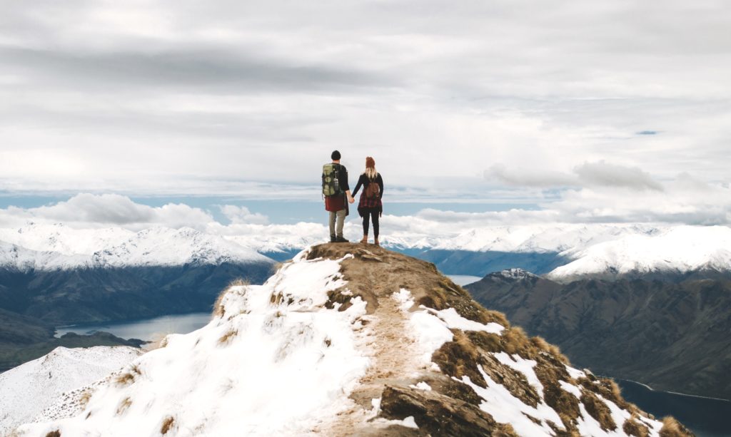 A couple holding hands on a mountaintop.