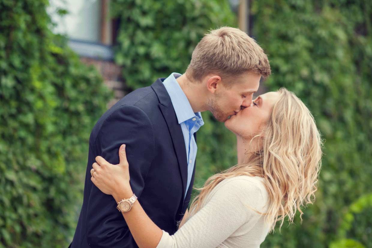 An engaged couple kissing.