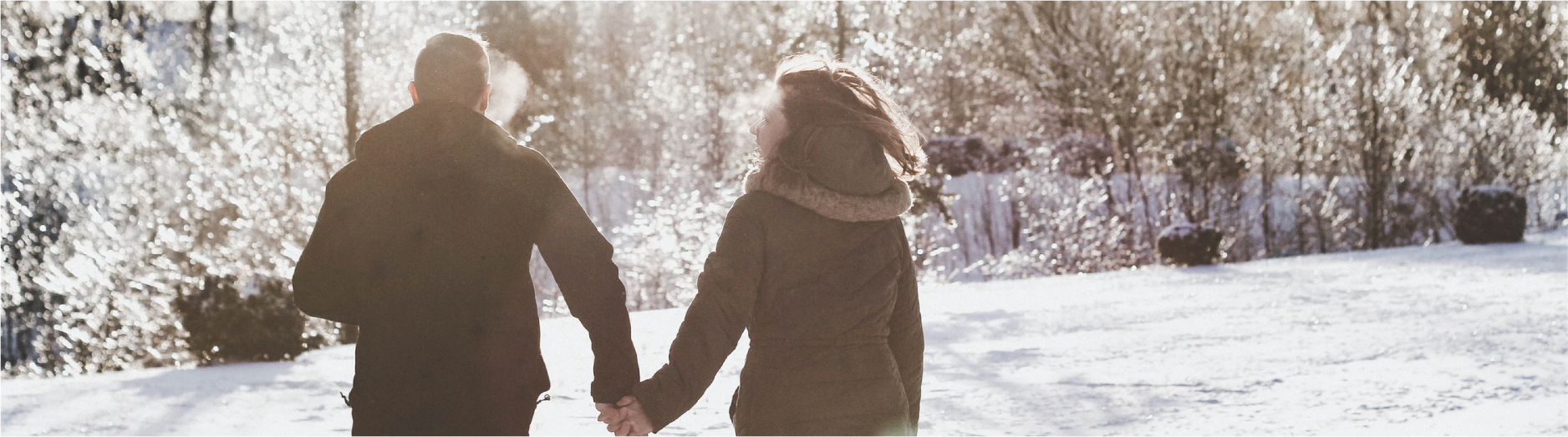 a couple holding hands and running through the snow - cropped to show only upper body