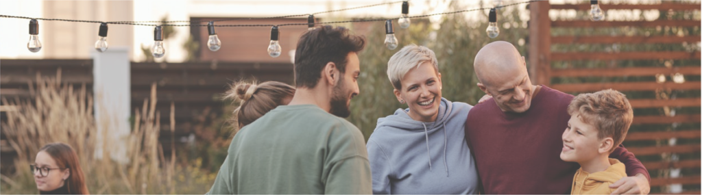 a family standing by a dinner table in a backyard, cropped to show only faces