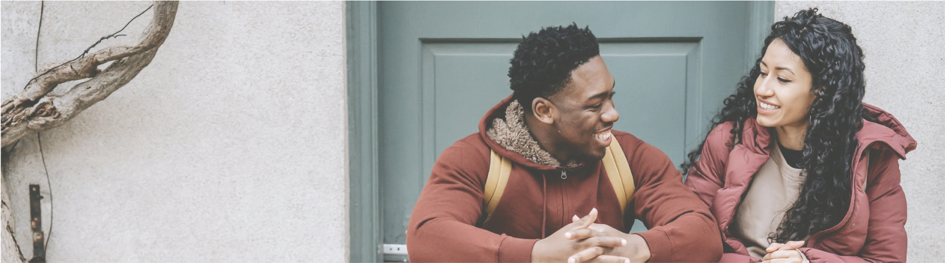 a smiling couple talking and sitting on a doorstep