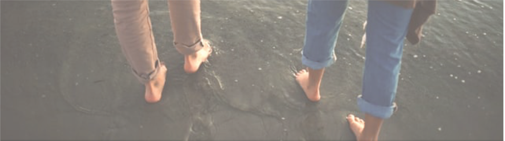 a couple holding hands walking into the surf on a beach