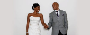 Newlyweds holding hands and staring in each other's eyes.