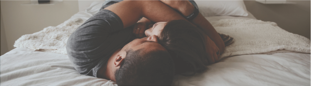 Couple cuddling together on their bed