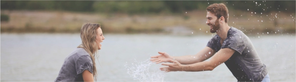 couple in lake splashing water on each other