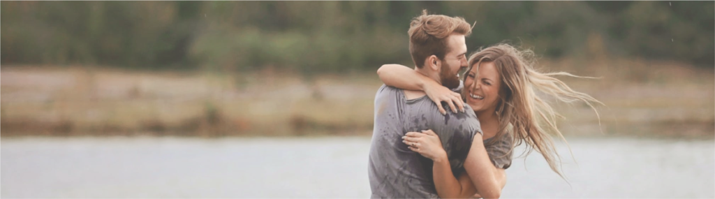 Man Hugging Laughing Woman While Standing in Body of Water