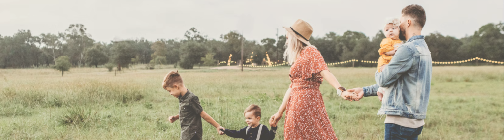 Family of five holding hands walking through meadow