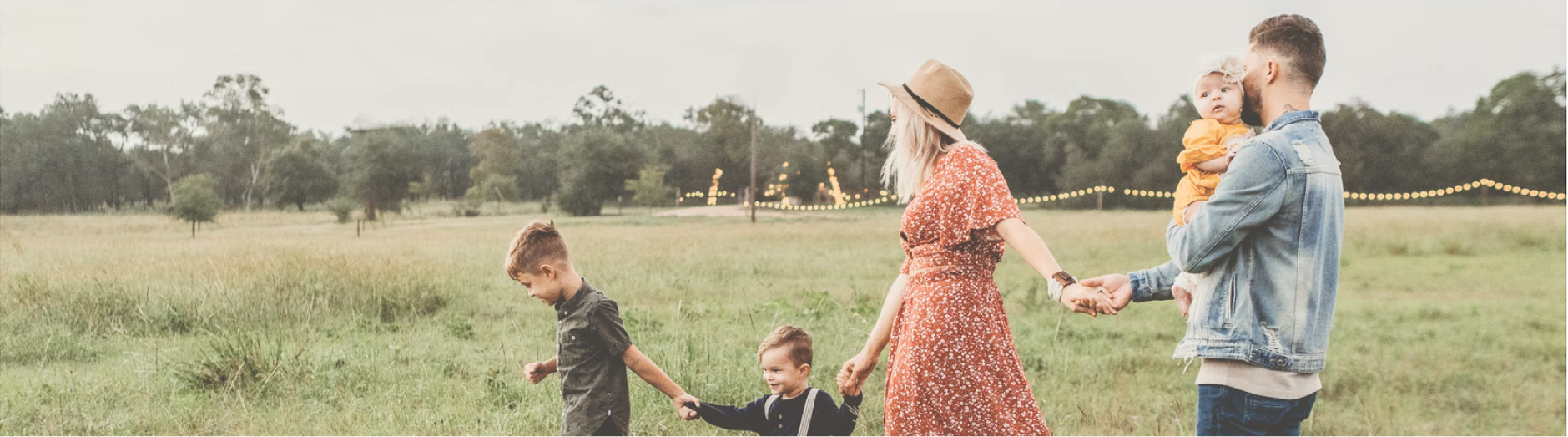 Family of five holding hands walking through meadow