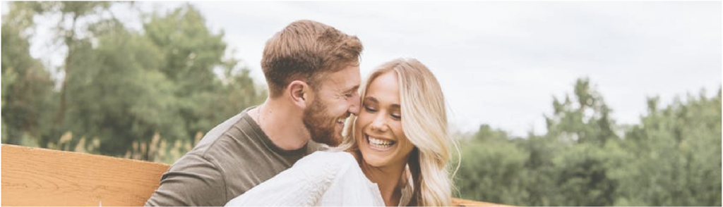 Smiling Couple Hugging Outdoors Leaning on a Wooden Fence