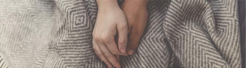 Couple's intertwined hands on blanket