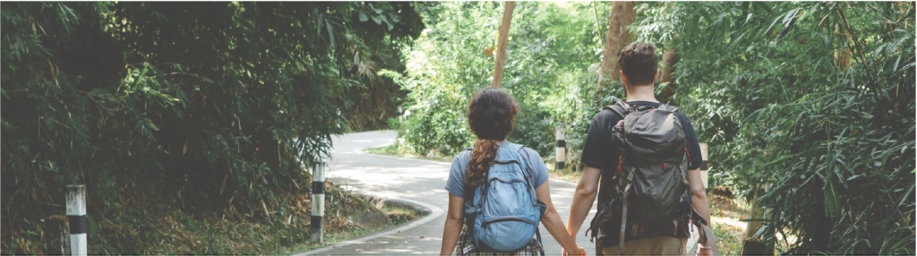 Couple holding hands while strolling on road in woods