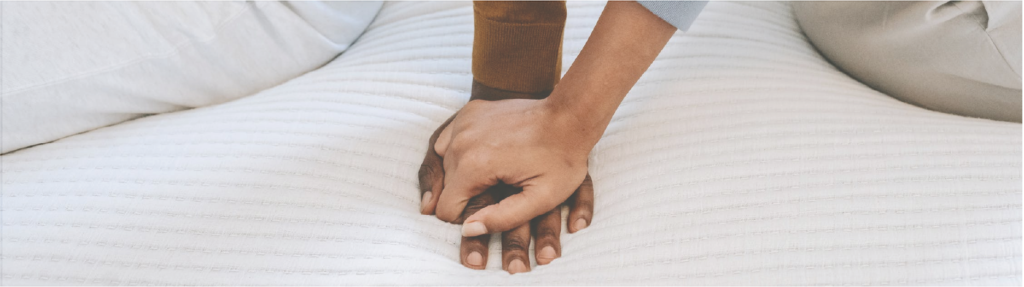 couple holding hands on bed